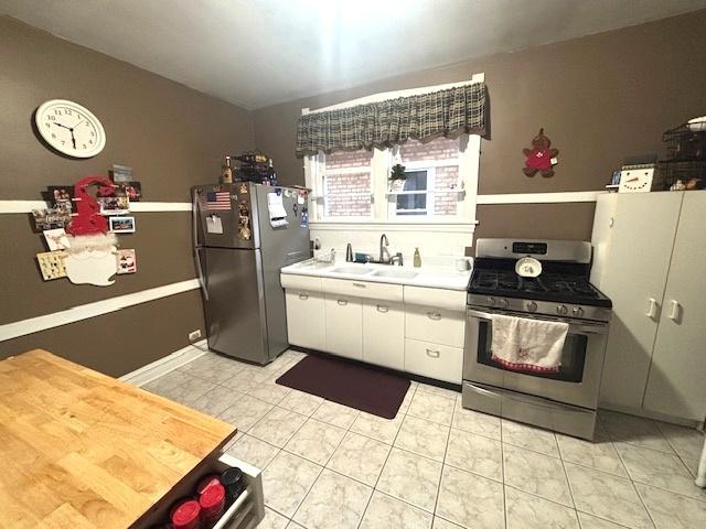 kitchen with white cabinets, sink, light tile patterned floors, and stainless steel appliances