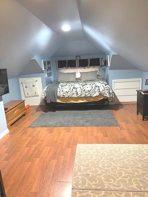 bedroom with wood-type flooring and lofted ceiling