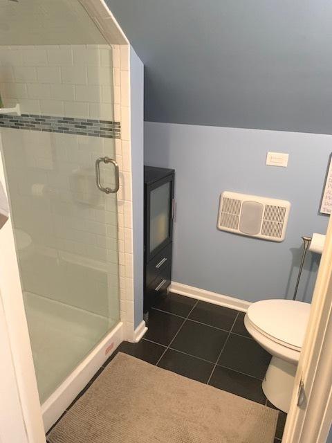 bathroom featuring toilet, vaulted ceiling, tile patterned floors, and an enclosed shower