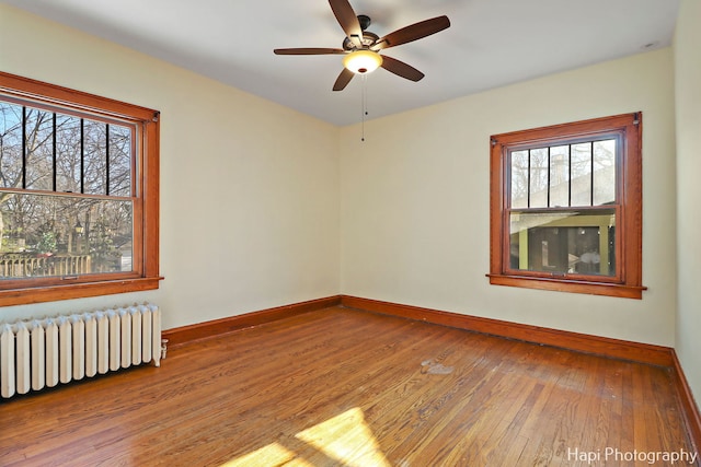 unfurnished room with ceiling fan, radiator, and hardwood / wood-style flooring