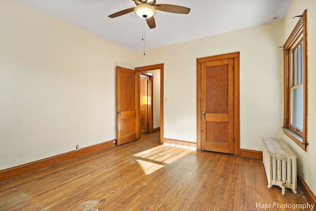 unfurnished bedroom featuring ceiling fan, radiator heating unit, and hardwood / wood-style flooring