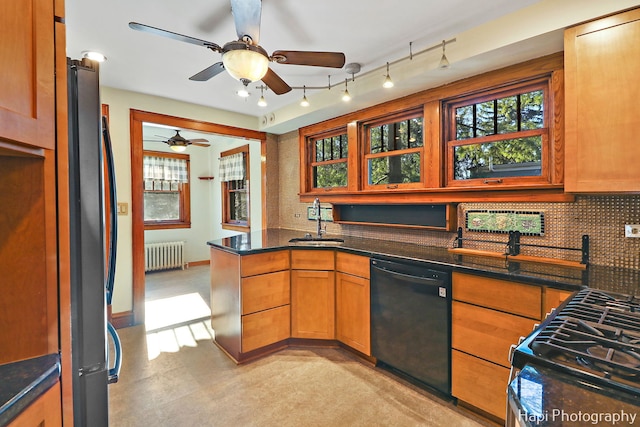 kitchen featuring radiator, black dishwasher, tasteful backsplash, sink, and stainless steel refrigerator