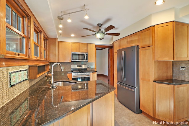 kitchen with ceiling fan, appliances with stainless steel finishes, backsplash, dark stone countertops, and sink