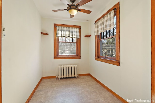 carpeted empty room with ceiling fan and radiator