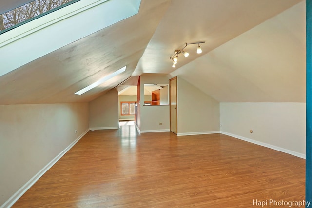 bonus room featuring lofted ceiling with skylight and light hardwood / wood-style floors