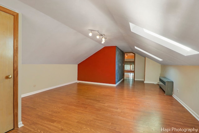 bonus room with hardwood / wood-style floors and lofted ceiling with skylight