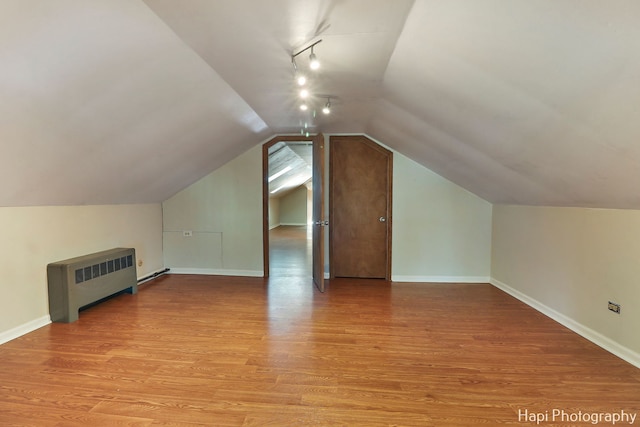 bonus room featuring radiator heating unit, lofted ceiling, and light wood-type flooring