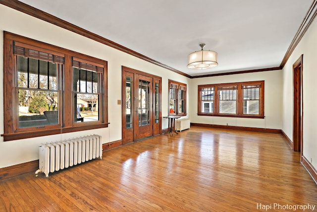 unfurnished room featuring hardwood / wood-style floors, radiator, and ornamental molding