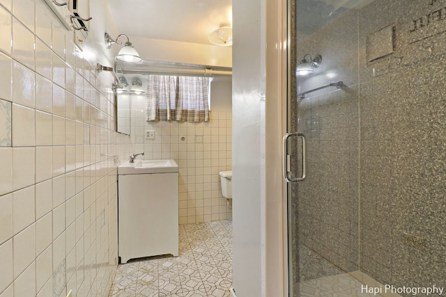 bathroom featuring toilet, tile patterned flooring, tile walls, walk in shower, and vanity