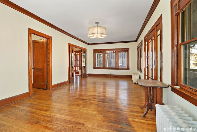 entryway with radiator heating unit, ornamental molding, and hardwood / wood-style floors