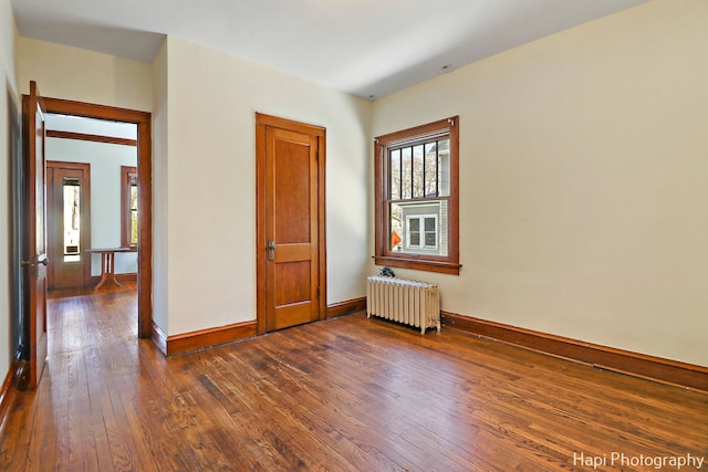 empty room with dark hardwood / wood-style floors and radiator