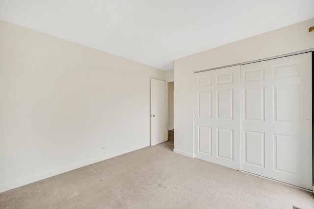 unfurnished bedroom with light carpet and a closet