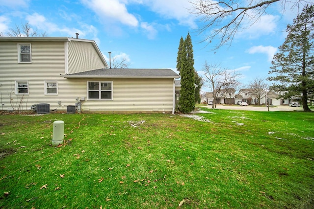 rear view of property featuring a lawn and cooling unit