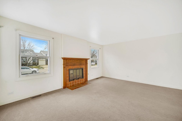 unfurnished living room with a tile fireplace and light colored carpet