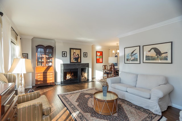 living area with a notable chandelier, ornamental molding, a high end fireplace, baseboards, and hardwood / wood-style flooring