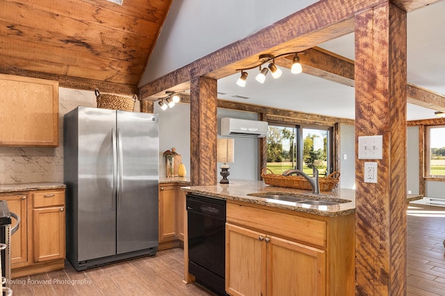 kitchen featuring light stone counters, sink, an AC wall unit, black dishwasher, and stainless steel refrigerator