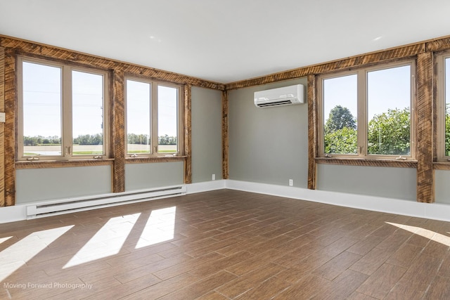 spare room with an AC wall unit, a wealth of natural light, hardwood / wood-style flooring, and a baseboard heating unit