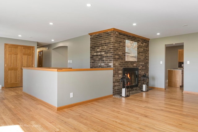 unfurnished living room featuring light wood-type flooring and a brick fireplace