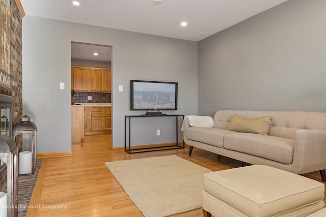 living room with a brick fireplace and light wood-type flooring