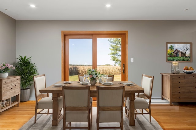 dining space with a baseboard heating unit and light hardwood / wood-style flooring