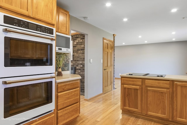 kitchen with black electric stovetop, double wall oven, and light hardwood / wood-style flooring