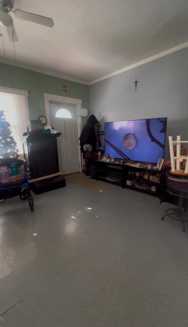 living room featuring ceiling fan, concrete flooring, and ornamental molding