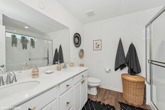 bathroom featuring hardwood / wood-style floors, vanity, toilet, and a shower with door