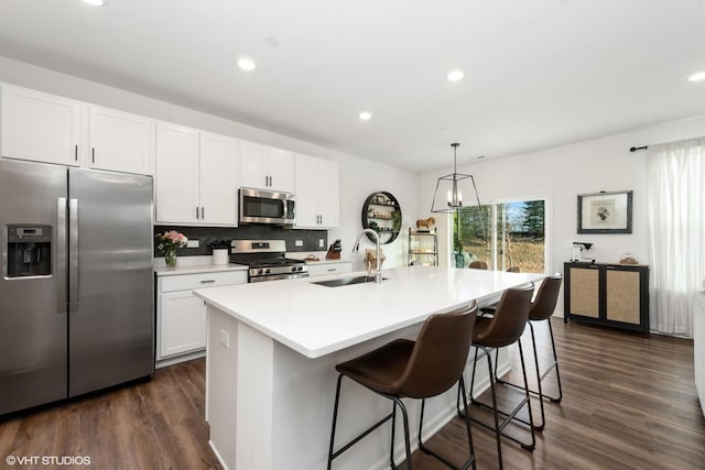 kitchen featuring white cabinetry, sink, stainless steel appliances, dark hardwood / wood-style floors, and an island with sink