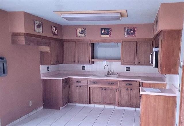 kitchen with backsplash, light tile patterned floors, and sink