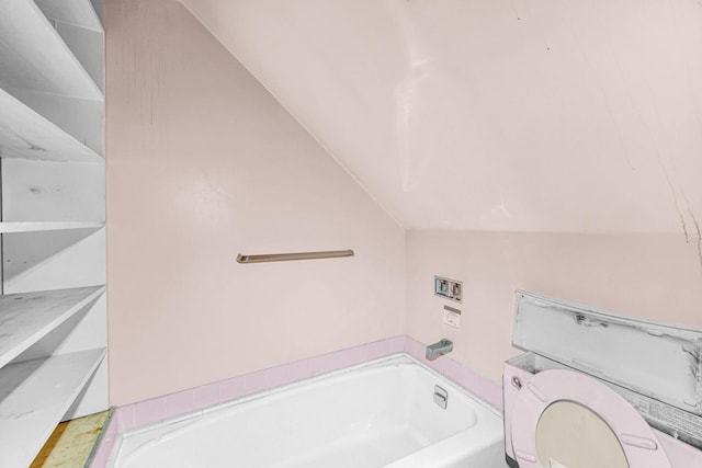 bathroom with a bathing tub, toilet, and lofted ceiling