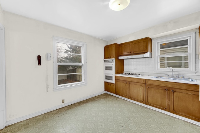 kitchen featuring decorative backsplash, white appliances, and sink