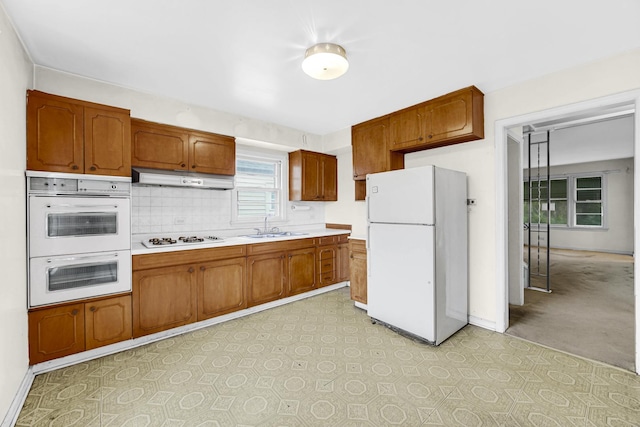 kitchen featuring backsplash, sink, and white appliances