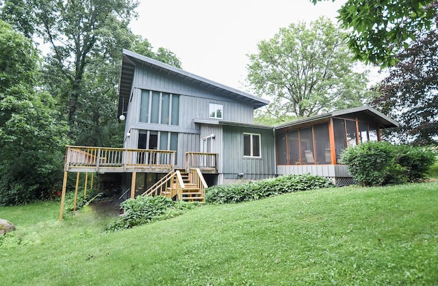 back of property featuring a lawn, a wooden deck, and a sunroom