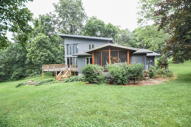 rear view of property featuring a sunroom, a yard, and a deck