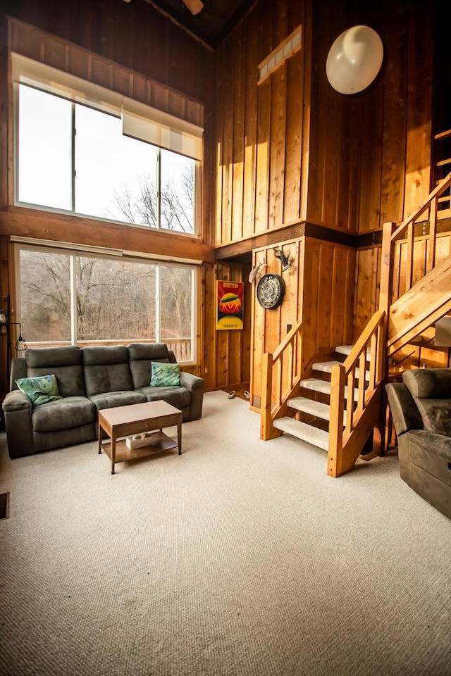 living room with wood walls, carpet floors, and a high ceiling