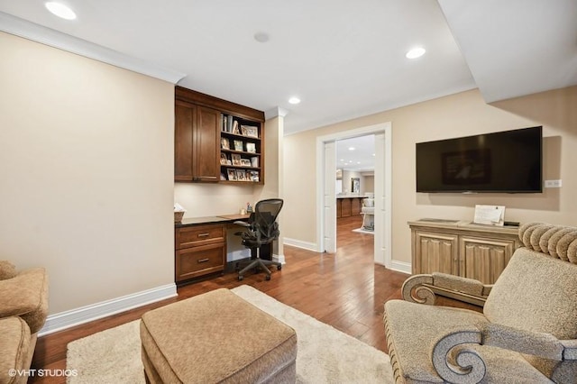 office featuring crown molding, dark wood-type flooring, and built in desk