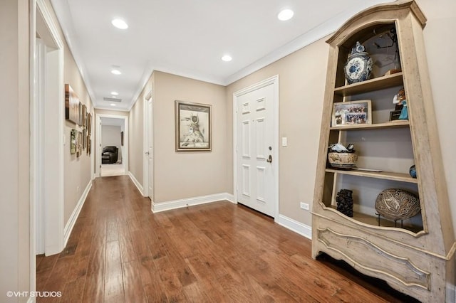 corridor with wood-type flooring and crown molding