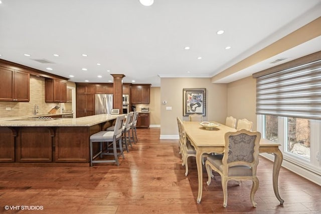 dining area featuring hardwood / wood-style floors, sink, and decorative columns