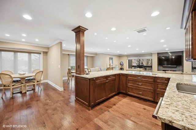 kitchen with light stone countertops, decorative columns, a wealth of natural light, and light hardwood / wood-style floors