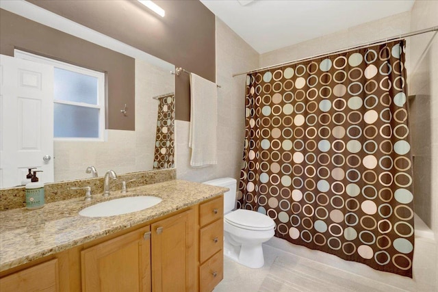 bathroom with vanity, tile walls, tile patterned floors, and toilet