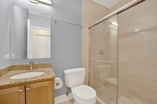 bathroom with vanity, a shower with door, and toilet