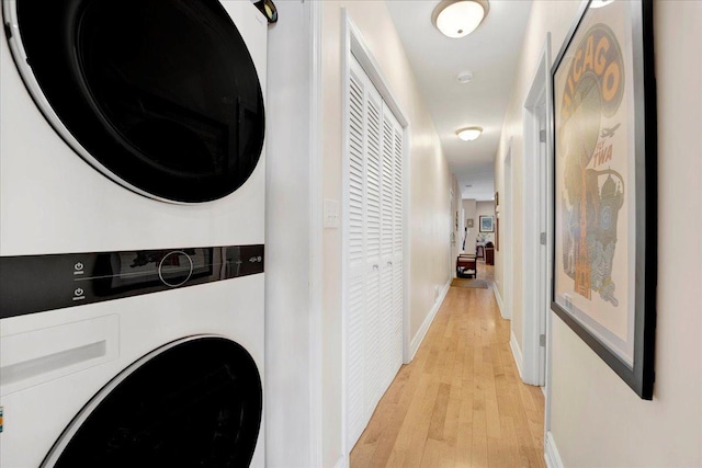 laundry area with light wood-type flooring and stacked washer / dryer