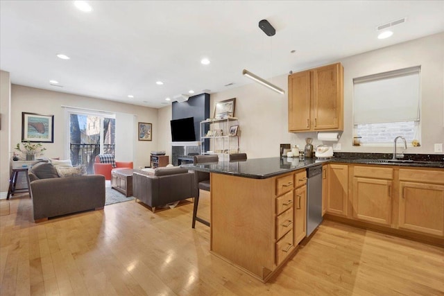 kitchen with dark stone countertops, a kitchen bar, stainless steel dishwasher, light hardwood / wood-style floors, and kitchen peninsula