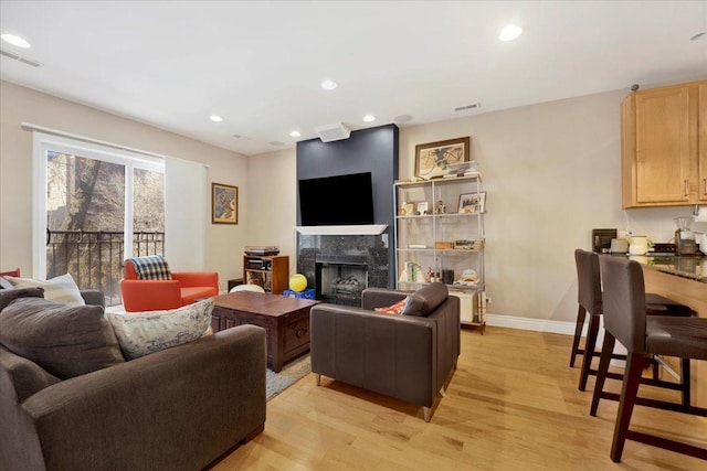 living room featuring a premium fireplace and light hardwood / wood-style flooring