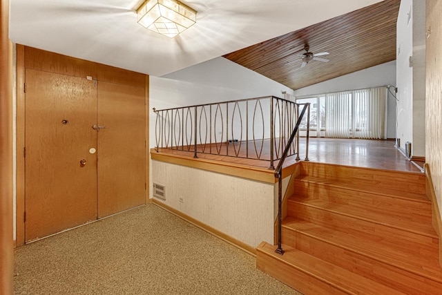 stairway with ceiling fan, carpet floors, wooden ceiling, and vaulted ceiling