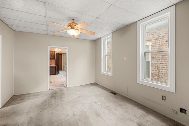 carpeted empty room with ceiling fan and a drop ceiling