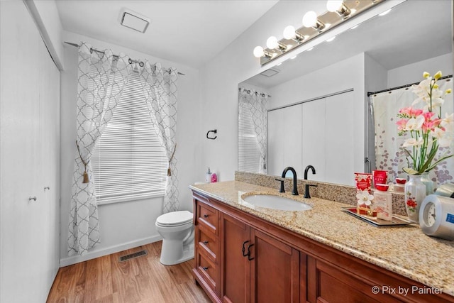 bathroom featuring a wealth of natural light, vanity, wood-type flooring, and toilet