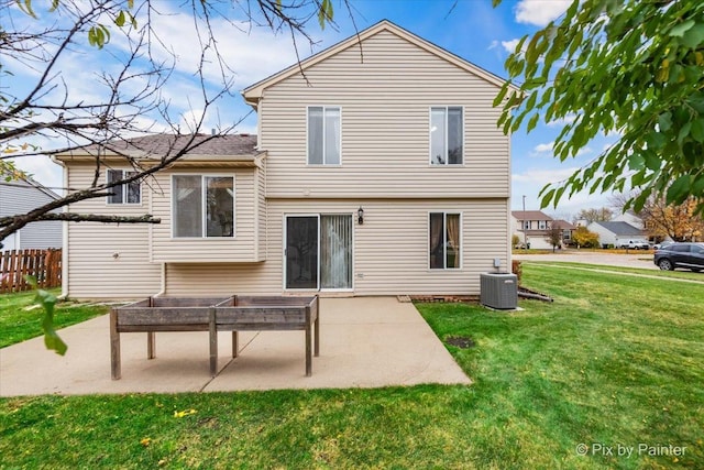 back of property with central air condition unit, a patio area, and a yard