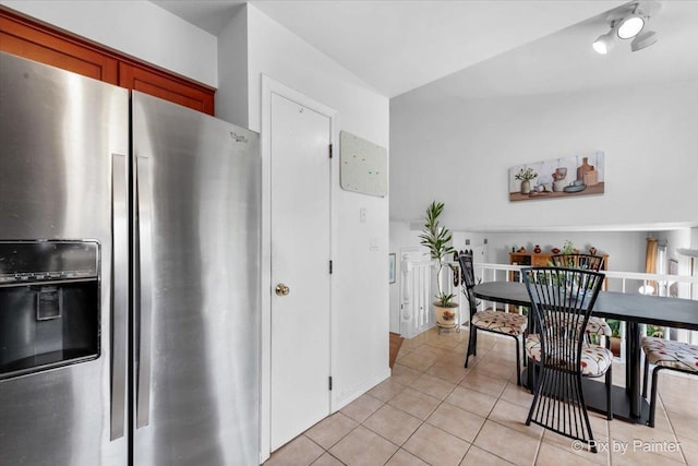 kitchen with stainless steel fridge, light tile patterned floors, and lofted ceiling