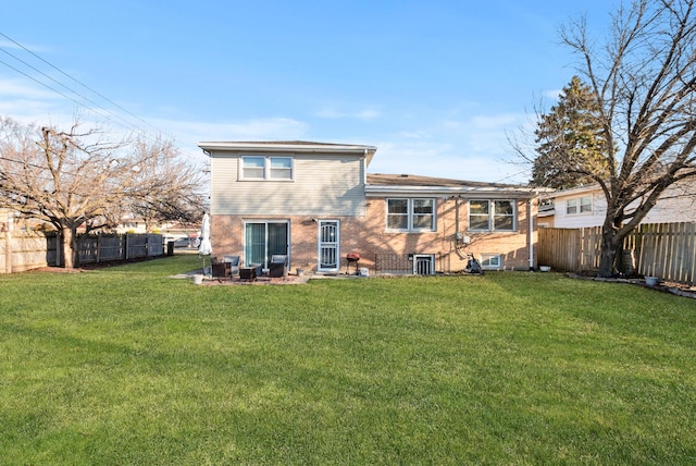 back of property featuring a yard, a fenced backyard, and brick siding